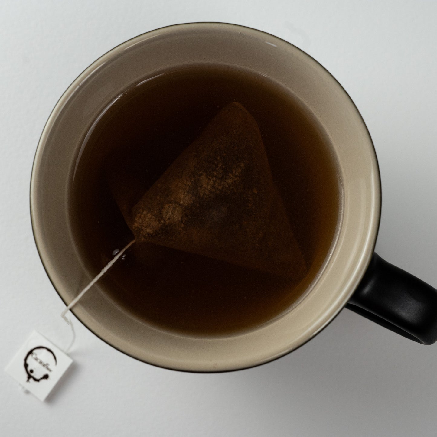 Single cup of cacao chocolate tea viewed from above showing cacao chocolate tea bag and cacao brew logo
