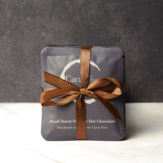 Organic Hot Chocolate Bundle, Valentine's Day gift set showing five single-serve sachets of Cacao Brew organic hot chocolate tied with a bow in dark brown ribbon.