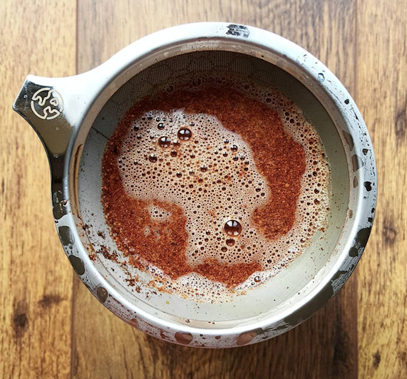 Overhead shot of a pour-over reusable filter in use filtering brewed cacao drinks