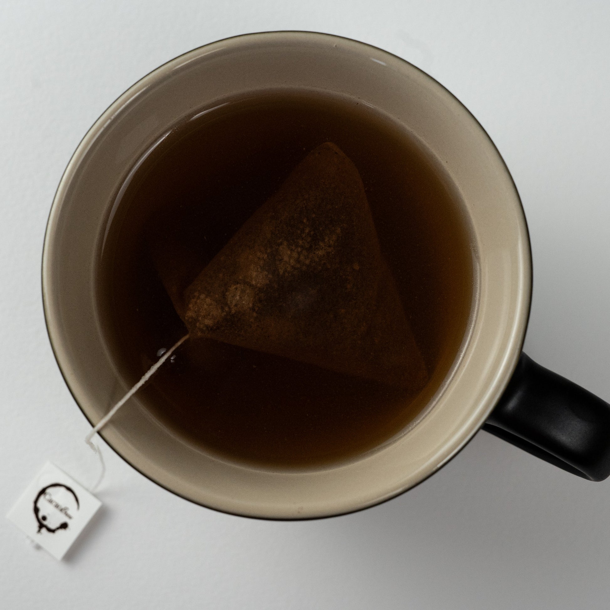 Single cup of cacao chocolate tea viewed from above showing cacao chocolate tea bag and cacao brew logo