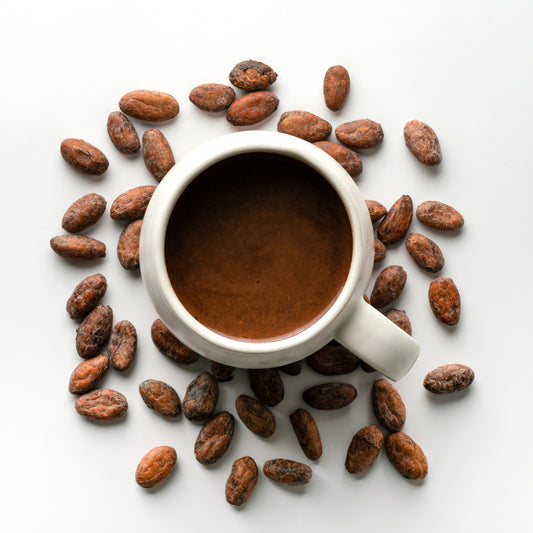 White mug filled with Philippine brewed cacao surrounded by cacao beans on a white background