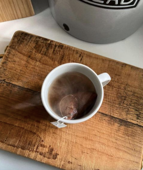 Steaming cup of Tanzania Cacao Chocolate tea on a wooden cutting board.